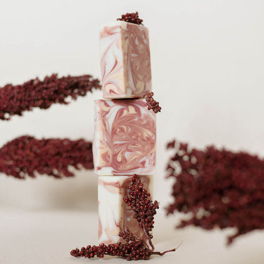 Stack of marbled handmade soap bars with dried berries n a light background