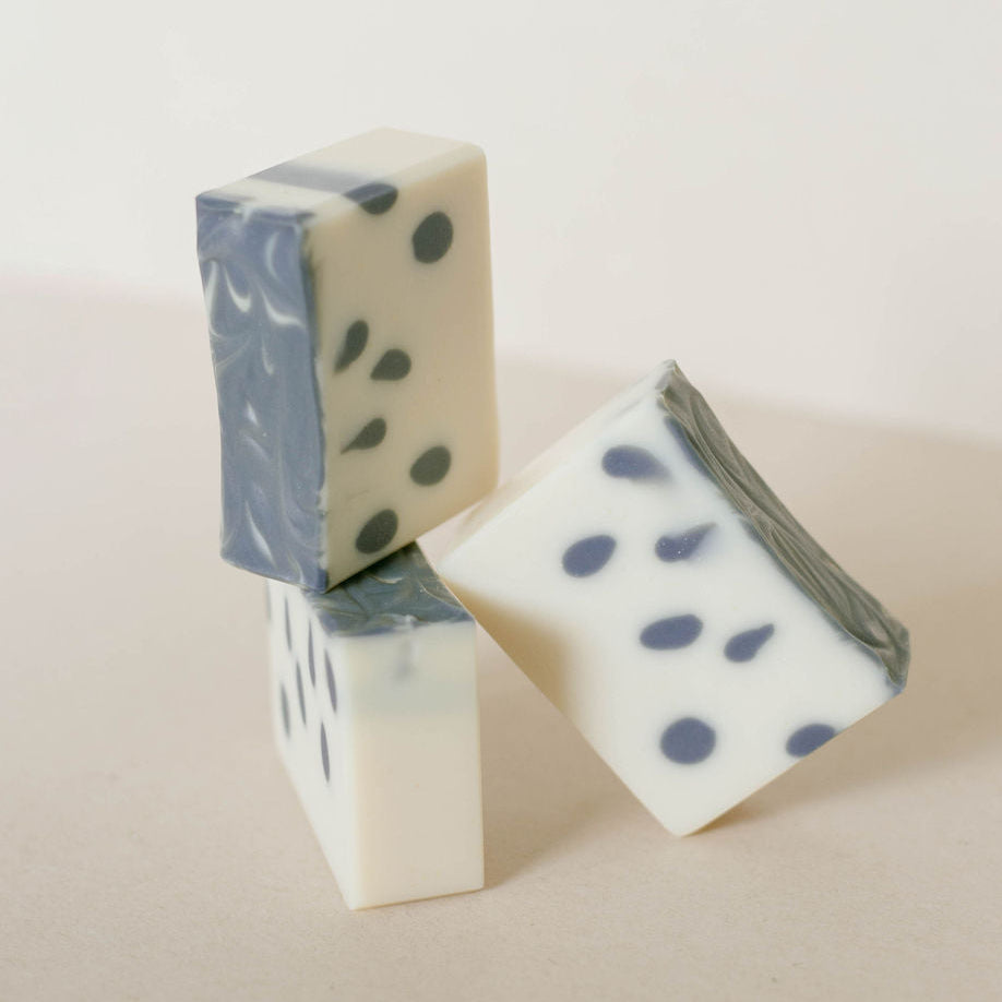 Three handmade bars of creamy white soap with navy tear drops throughout.