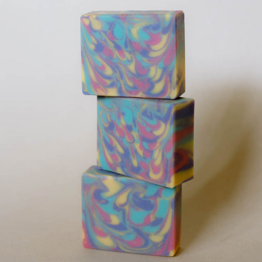 Three bars of handmade soap colored with peacock feather swirls of puple, teal, yellow and magenta.