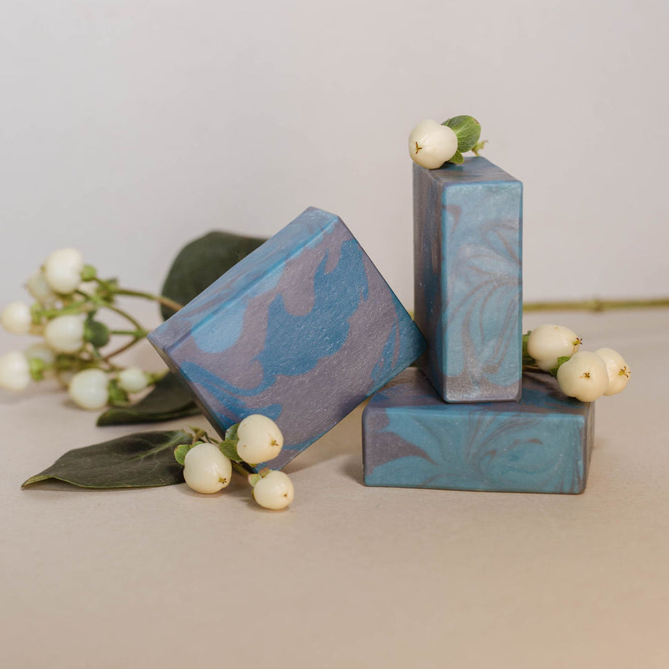 Three handmade bars of soap accented with jasmine flowers and scented with Bramble Berry's cardamom and cedar fragrance oil.