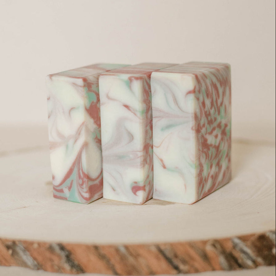 Marble-patterned handmade soaps on a textured wooden surface with a neutral background.