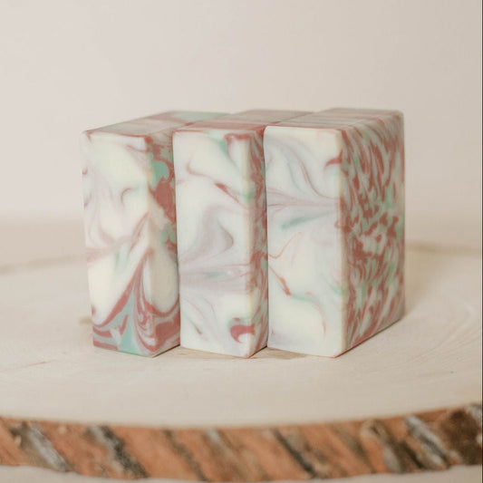 Marble-patterned handmade soaps on a textured wooden surface with a neutral background.