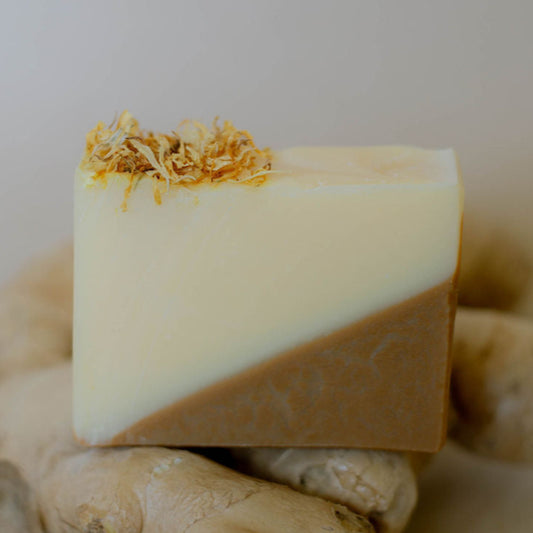 Handmade bar of soap with triangular coloring made with orange clay, topped with dried calendula flowers.