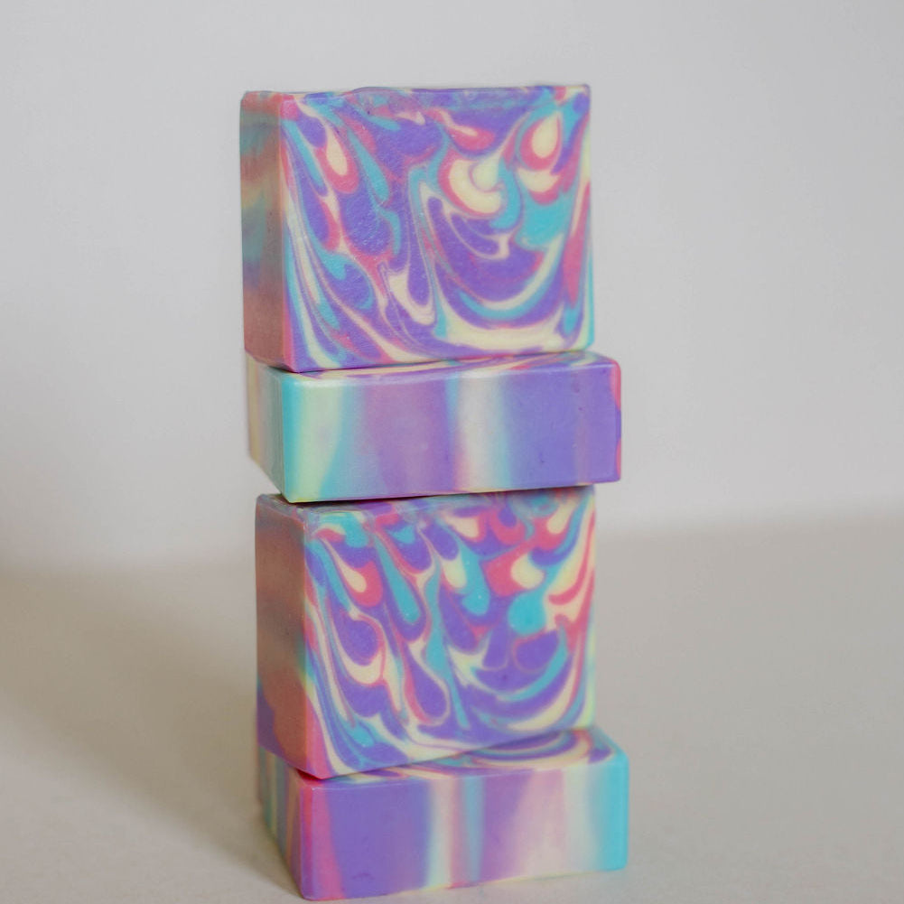 Four handmade bars of soap stacked vertically. Colored with drop swirls of purple, yellow, pink and teal. Scented with Bramble Berry's Lychee Red Tea fragrance oil.