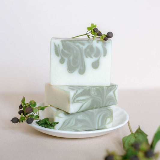 Three handmade bars of soap stacked vertically. Olive green drop swirls on creamy white bars. Scented with vetiver and sandalwood fragrance oils.