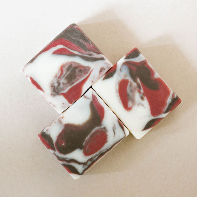 Marbled soap bars with red and brown patterns on a beige background