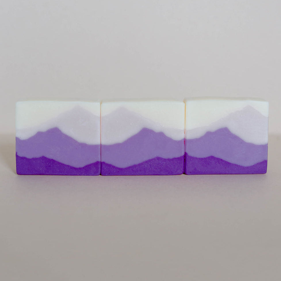 Three handmade bars of soap made with shades of purple mountain landscapes.