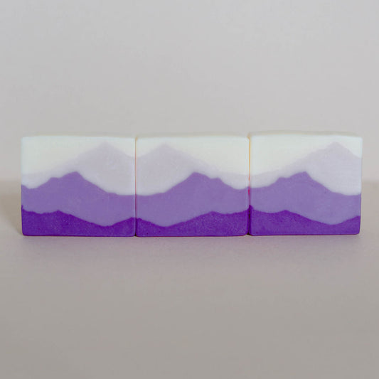 Three handmade bars of soap made with shades of purple mountain landscapes.