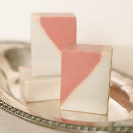 Three geometrically shaped handmade soap bars on a silver tray with a white background