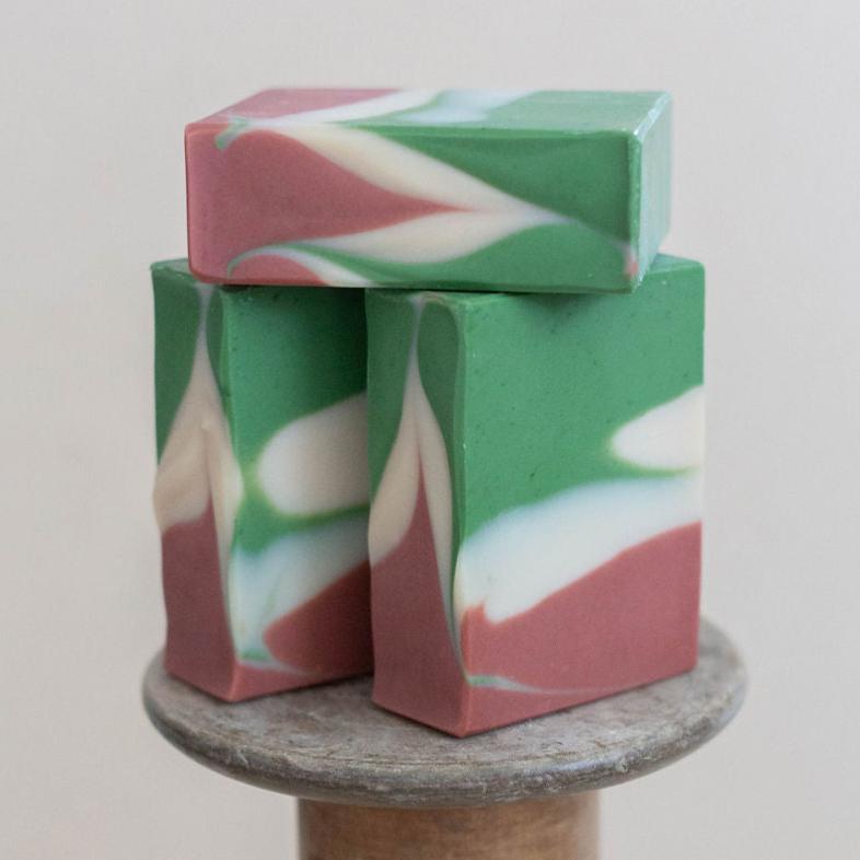 Three handmade bars of soap colored in rust red, green and white. Scented with Bramble Berry's lingonberry spice fragrance oil.