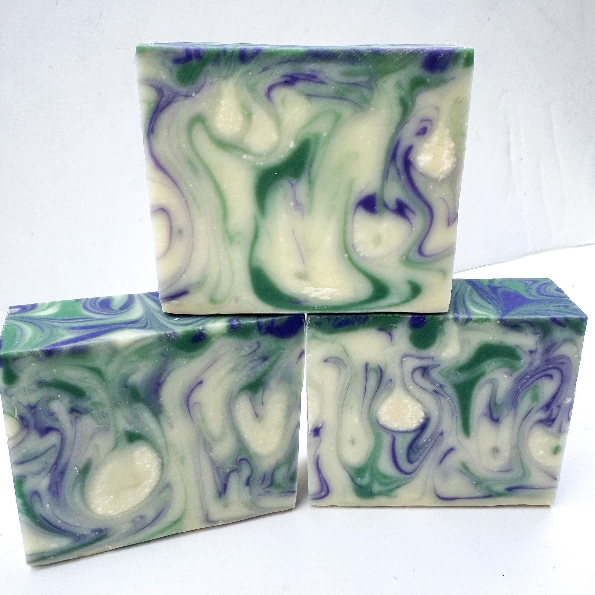 Three swirled soap bars in green, white, and purple on a white background