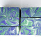 Marbled green and purple soap bars on a white background