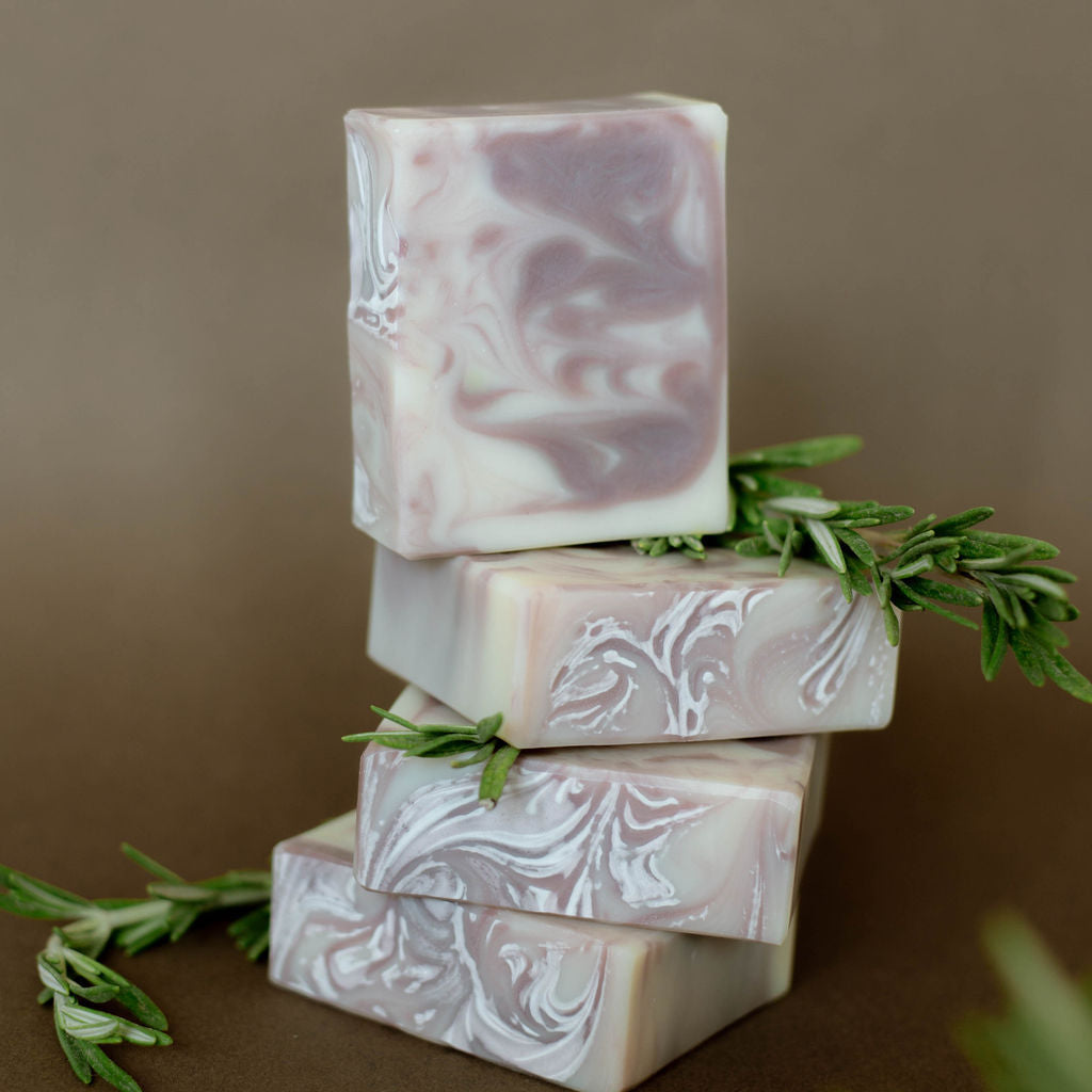 Four handmade bars of soap colored with swirls of purple clay.