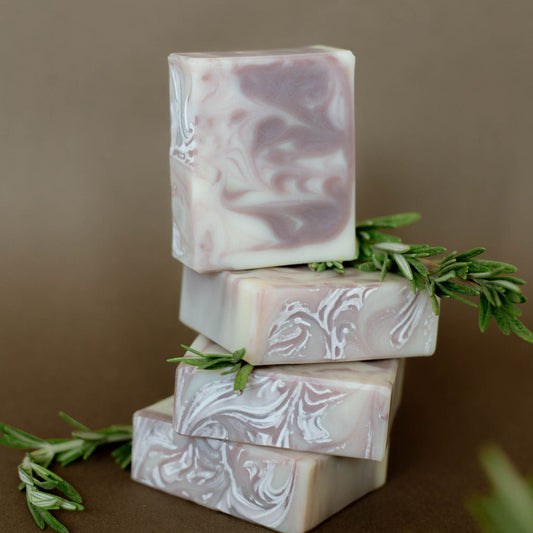 Four handmade bars of soap colored with swirls of purple clay.