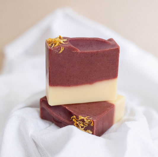 Two handmade bars of soap colored with deep mauve from madder root powder. Scented with a blend of orange and clove essential oils.