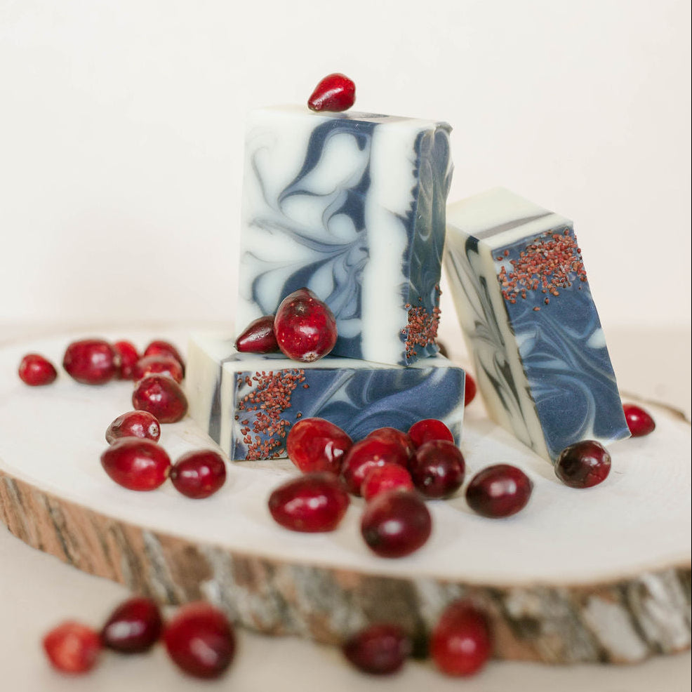 Black marble-patterned  handmade soap bars with red berries on a wooden surface